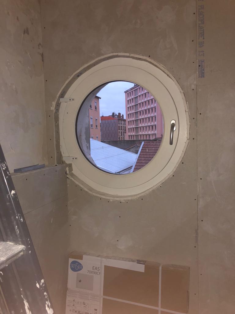 Fenêtre ronde type hublot intégrée dans un doublage en plaques de plâtre BA13 vissées, avant pose des bandes et de l’enduit