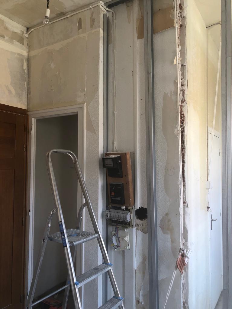 Murs décapés d’un appartement ancien, ancien tableau électrique et montants métalliques d’une future cloison